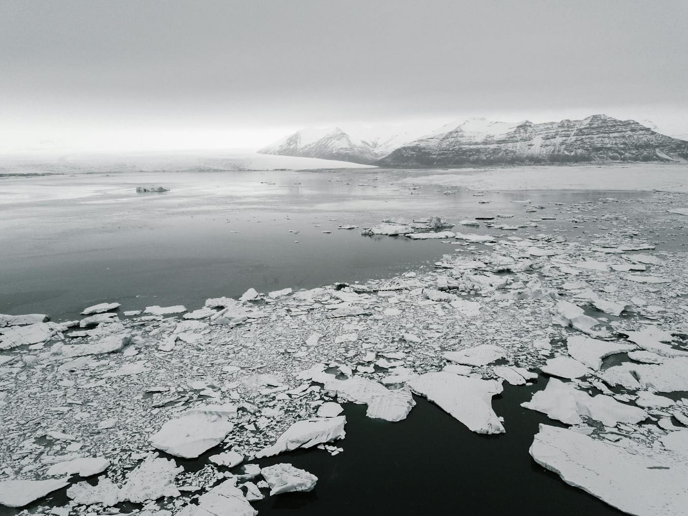 antarctic landscape with broken ice on water and frozen mounts